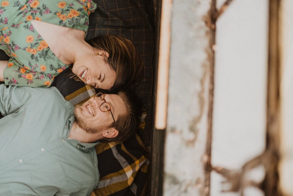 A couple laying on a bed in an old barn.
