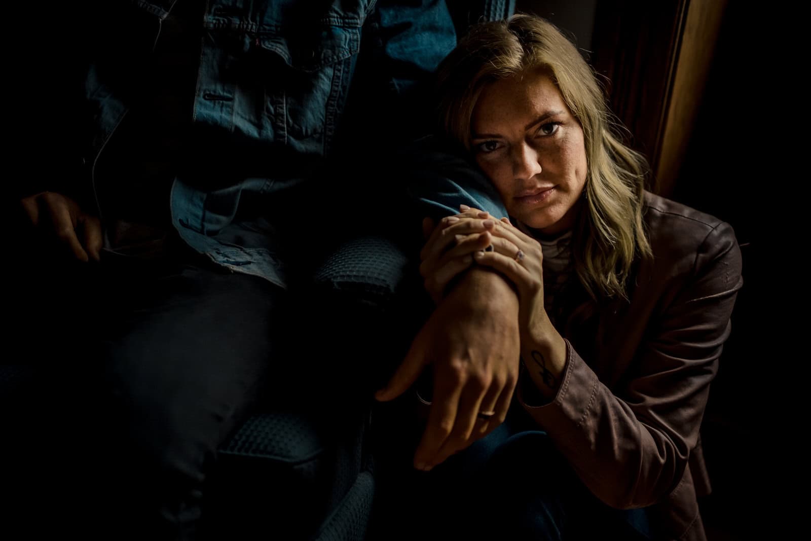 A woman is sitting on a chair in the dark.