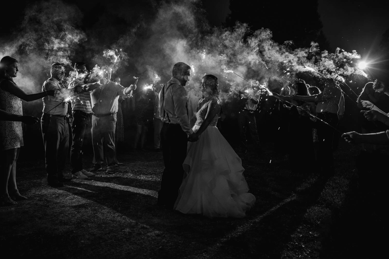 A bride and groom holding sparklers in the dark.