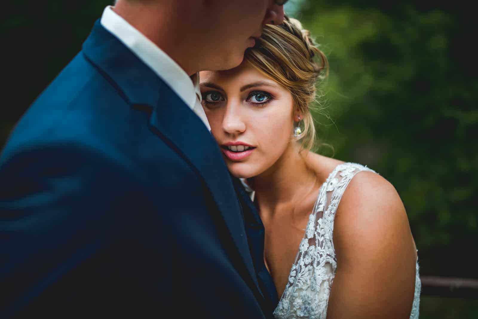 A bride and groom embracing in the woods.