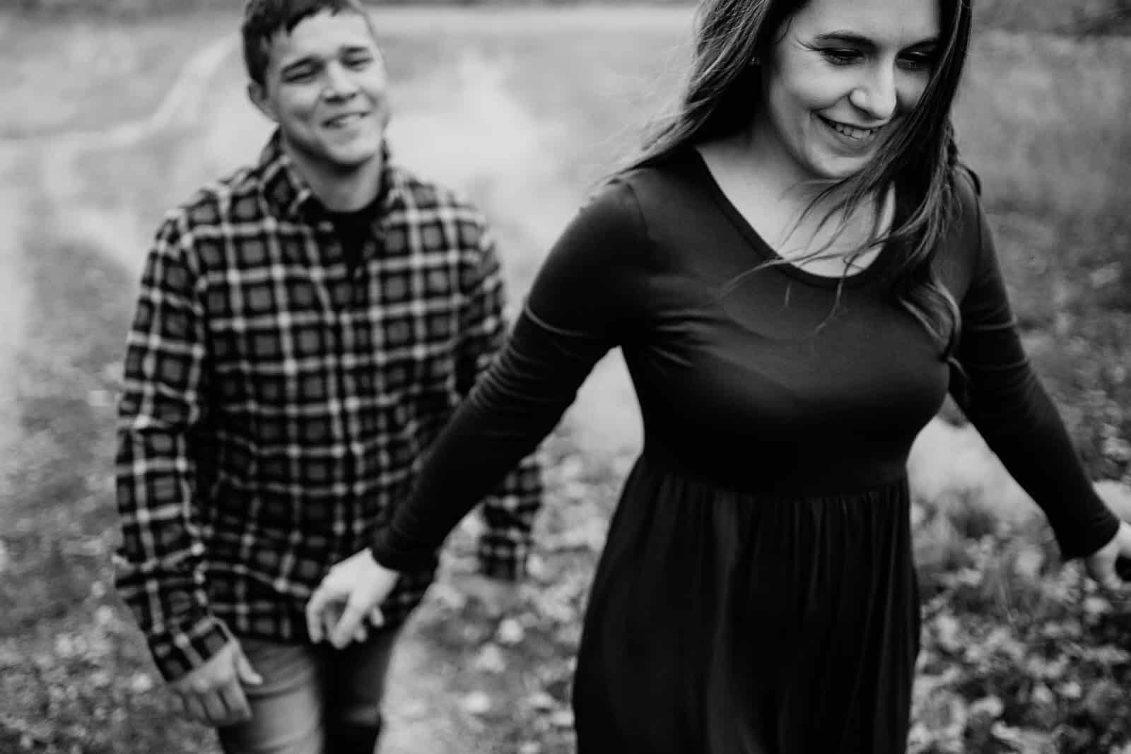 A black and white photo of a couple walking in a field.