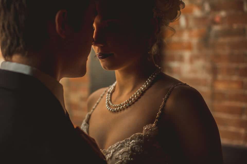 A bride and groom embracing in front of a brick wall.