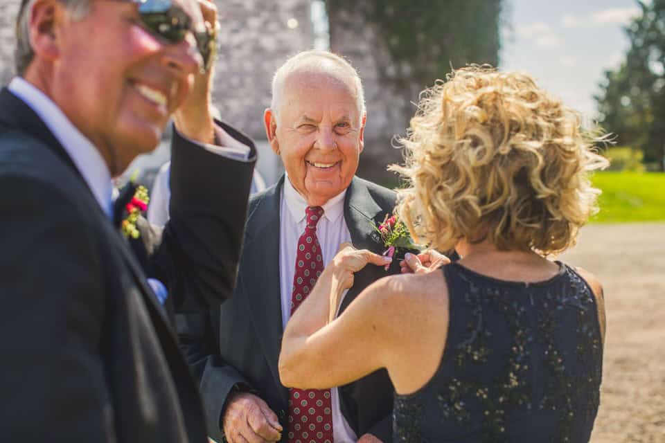 A man is putting a flower on a man's shirt.
