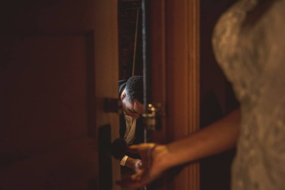 A bride and groom looking at each other through a door.
