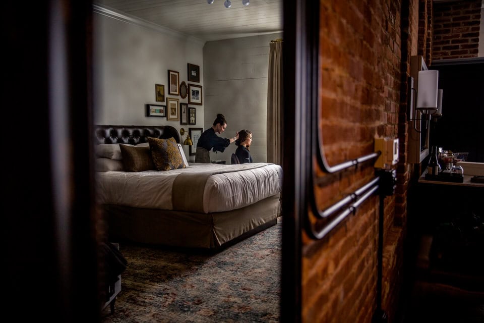 A woman is standing in front of a bed in a room.