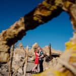 A couple is posing in front of a pile of rocks.