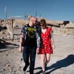 A man and a woman walking through a desert.