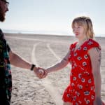 A man and a woman holding hands in the sand.
