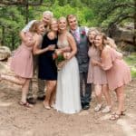 A bride and her bridesmaids pose for a photo in the woods.
