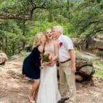 A bride and groom kissing in the woods.