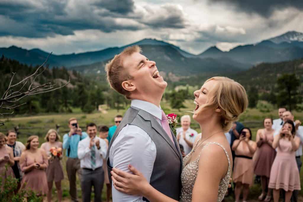 A Denver CO photographer captures a bride and groom sharing a kiss in front of their guests at an elopement in Rocky Mountain National Park