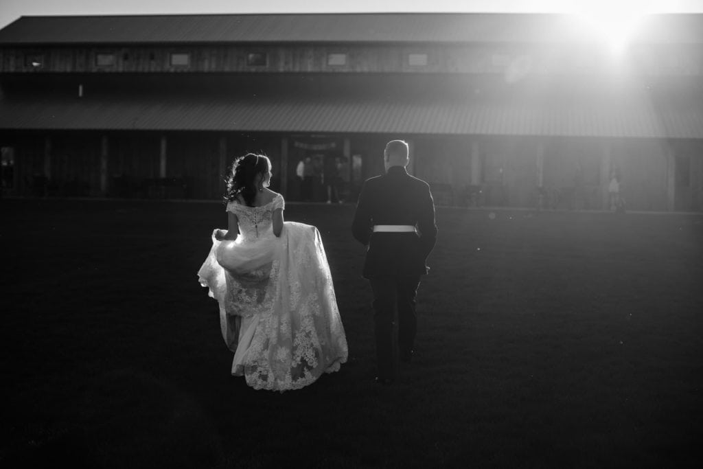 A La Crosse WI wedding photographer captures a bride and groom walking in front of a barn.