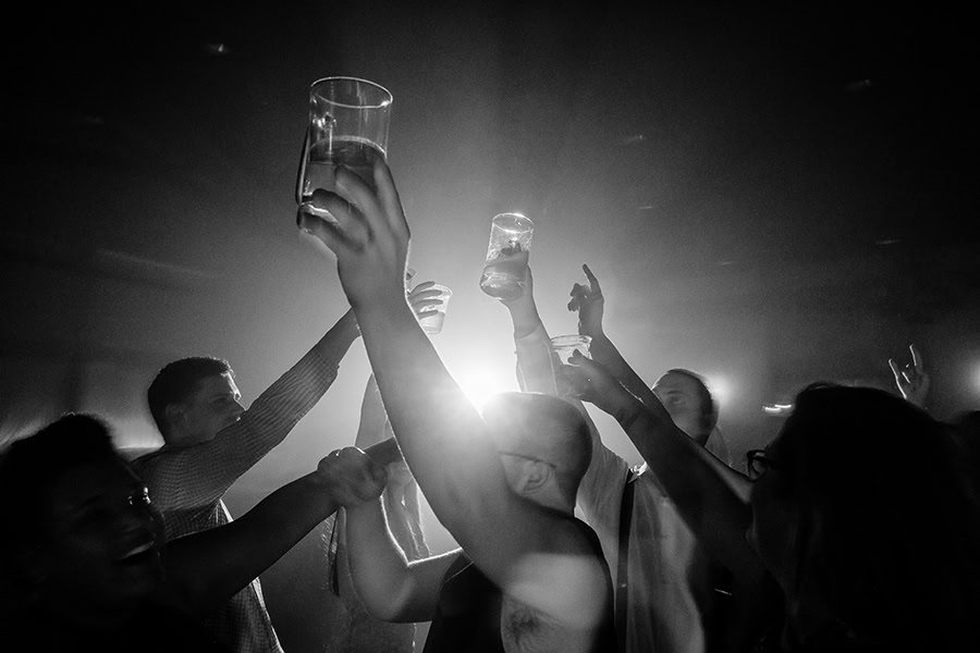 A black and white photo of a group of people raising their glasses.