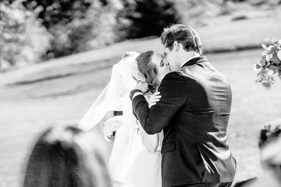 A bride and groom kiss during their wedding ceremony.