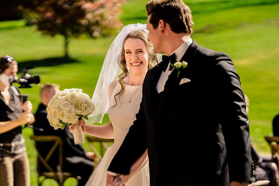 A bride and groom walking down the aisle at a wedding.