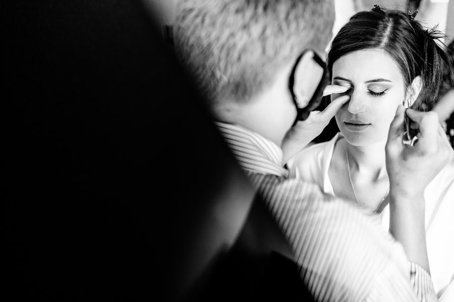 A woman is getting her makeup done in a black and white photo.