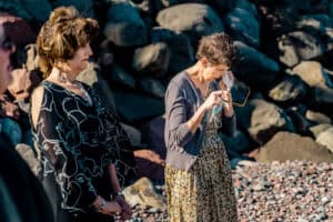Two women standing next to each other on a rocky beach.