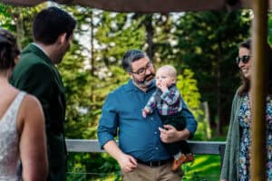 A man holding a baby in front of a group of people.