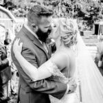 A bride and groom share an emotional kiss in front of a rustic barn at their backyard wedding in La Crosse.