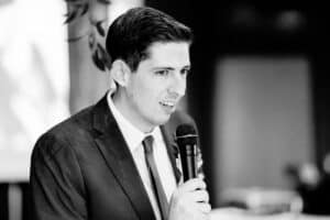 A man in a suit speaking into a microphone.