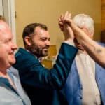 A group of men celebrating Courtney and James' love-filled wedding by giving each other high fives in their backyard.