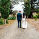 A bride and groom walking down a dirt path.