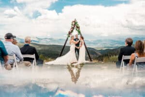 A wedding ceremony in the mountains with clouds in the background.