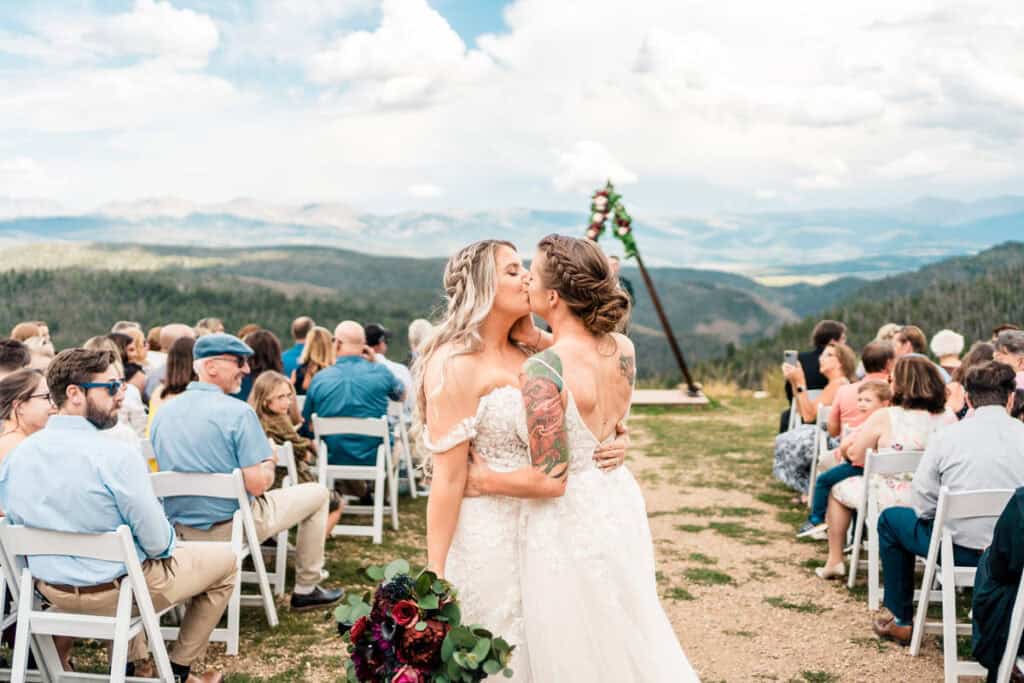 gay couple gets married granby ranch013 Two brides kissing at their wedding ceremony in the mountains.