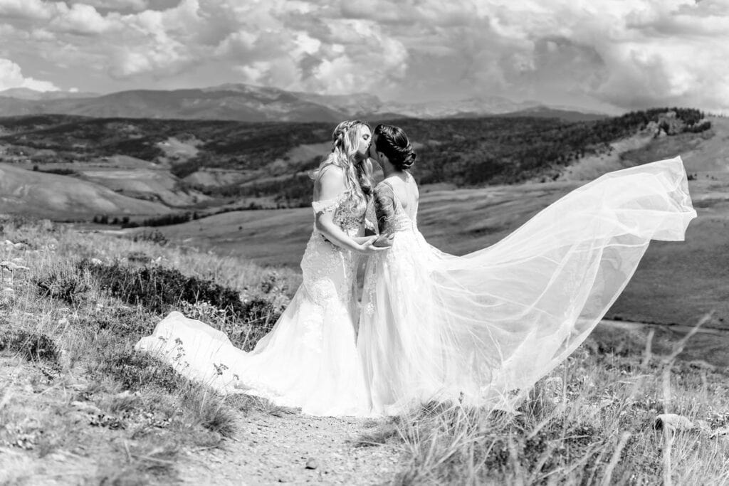 gay couples takes photos on peak of granby lake co004 Two brides kissing on a hillside in a black and white photo.