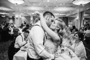 A bride and groom embrace and kiss on the dance floor at their Colorado Parks wedding venue while guests watch and dine in the background.