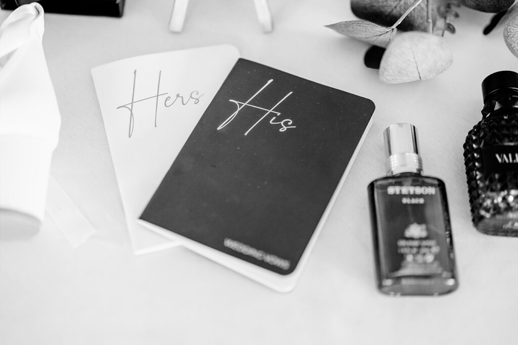 hers-his-vow-books-perfume-details-maple-grove-events-wedding.jpg Wedding guest book with 'Hers' and 'His' labels, surrounded by perfume and decorative items, at Maple Grove Events.