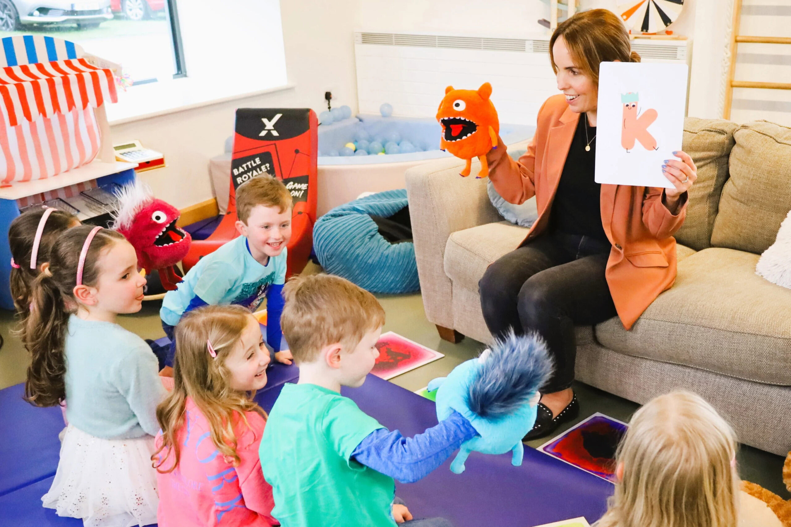 A group of children captivated by Fuzzle the Speech Monster during a session