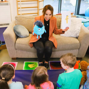 Woman leading a mindfulness session with children in a colourful therapy room.