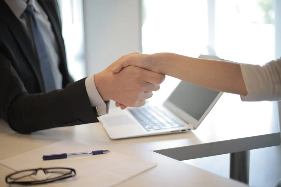 A picture of a white man shaking a white woman's hand at a job interview.