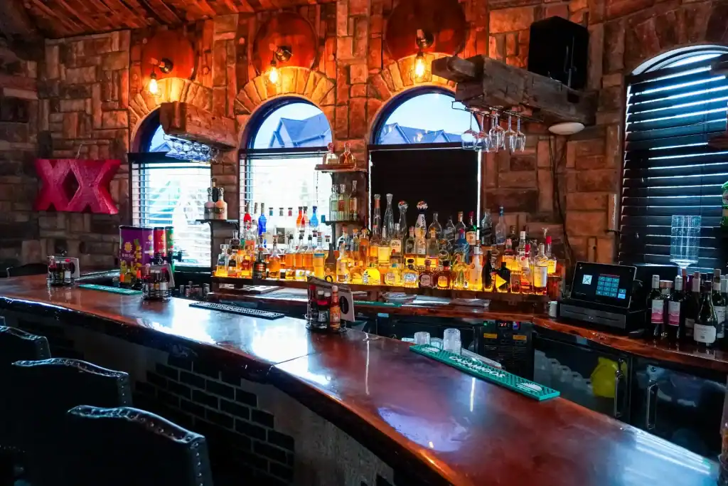 Bar area with illuminated bottles and rustic brick walls.