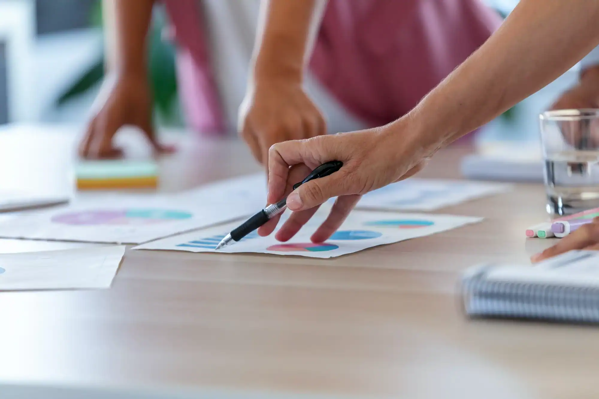 The hands of business people pointing at the statistics of the company in the office.