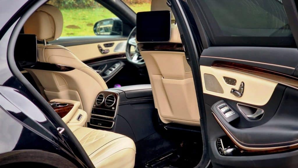 Luxury rear interior of a Mercedes S-Class with cream leather seats and executive comfort features