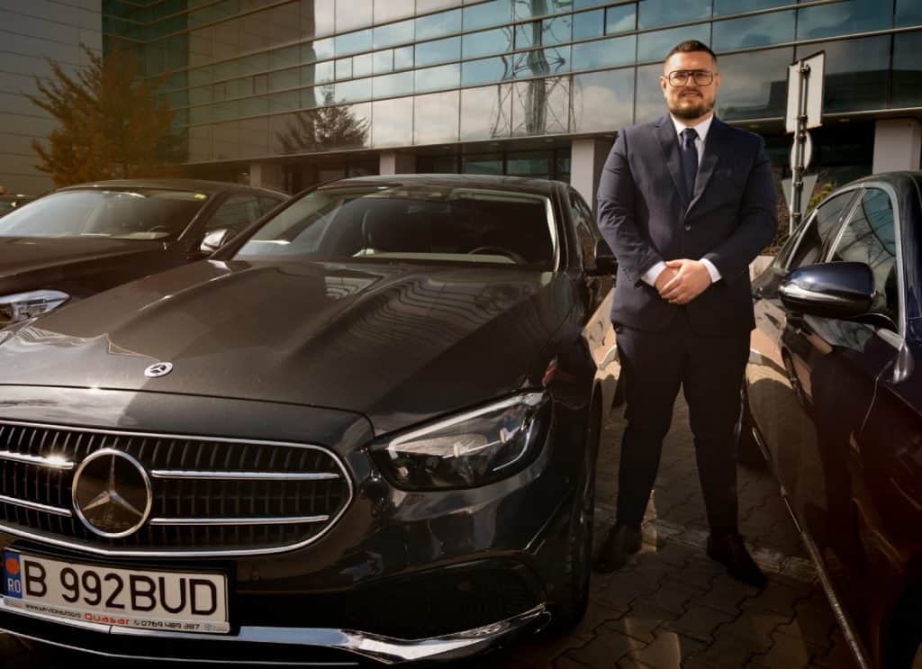 Professional chauffeur standing next to a Mercedes E-Class from the Bud’s Cab fleet in Bucharest
