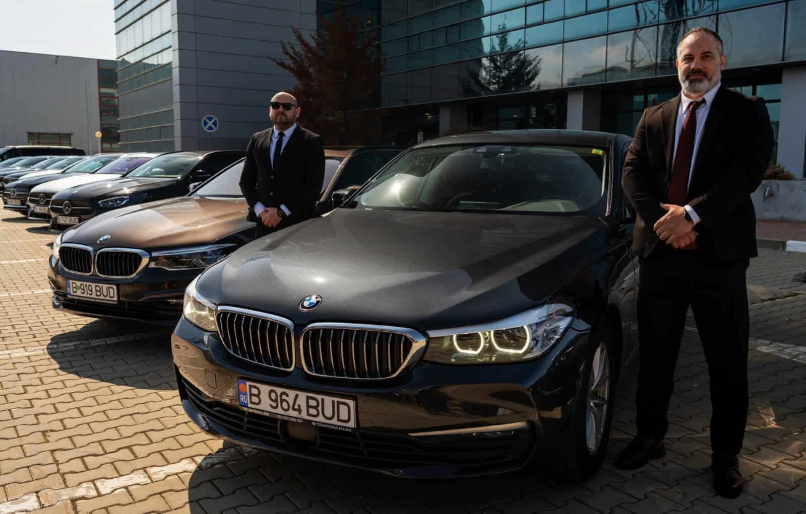 Professional chauffeurs standing beside BMW vehicles from the Bud’s Cab fleet