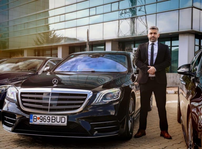 Professional chauffeur standing next to a Mercedes S-Class from the Bud’s Cab fleet