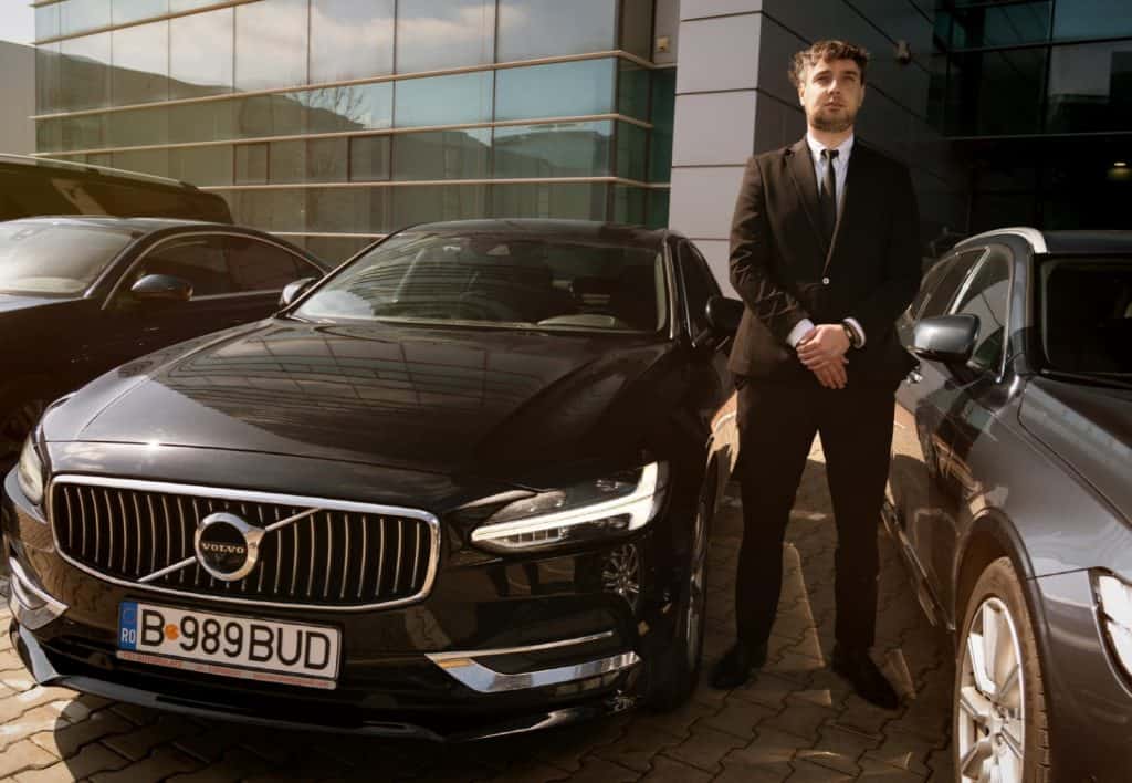 Professional chauffeur standing next to a Volvo S90 from the Bud’s Cab fleet in Bucharest