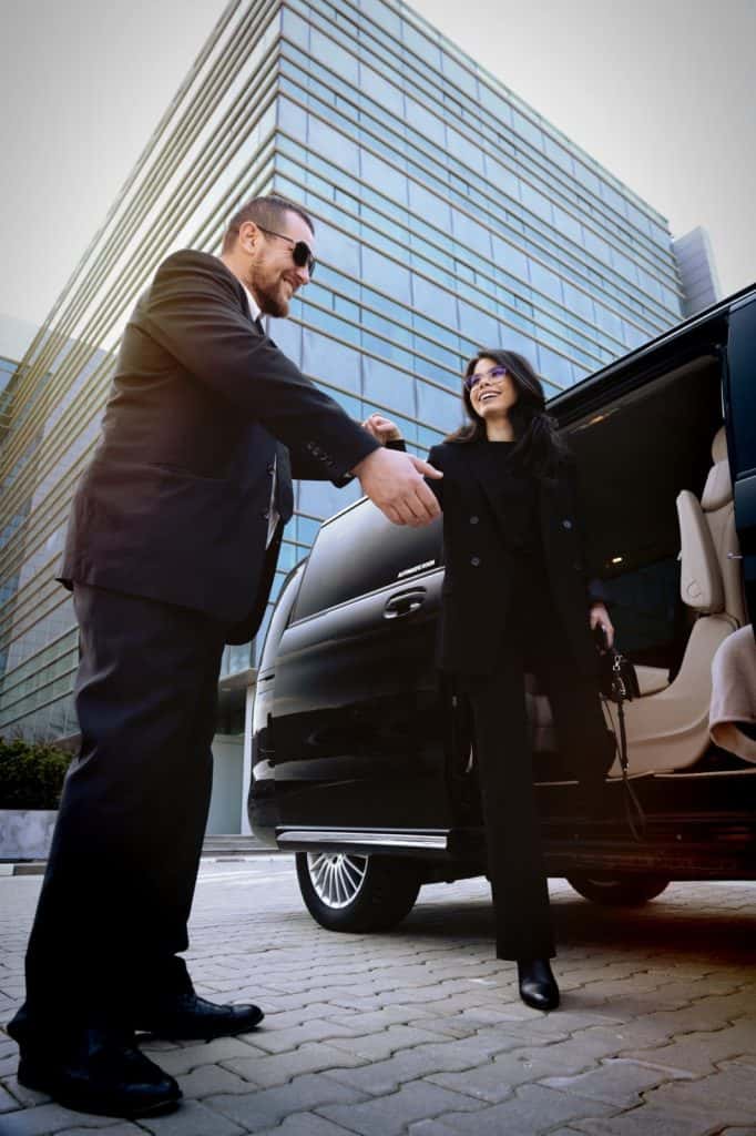 Professional chauffeur welcoming a passenger beside a Mercedes V-Class in Bucharest