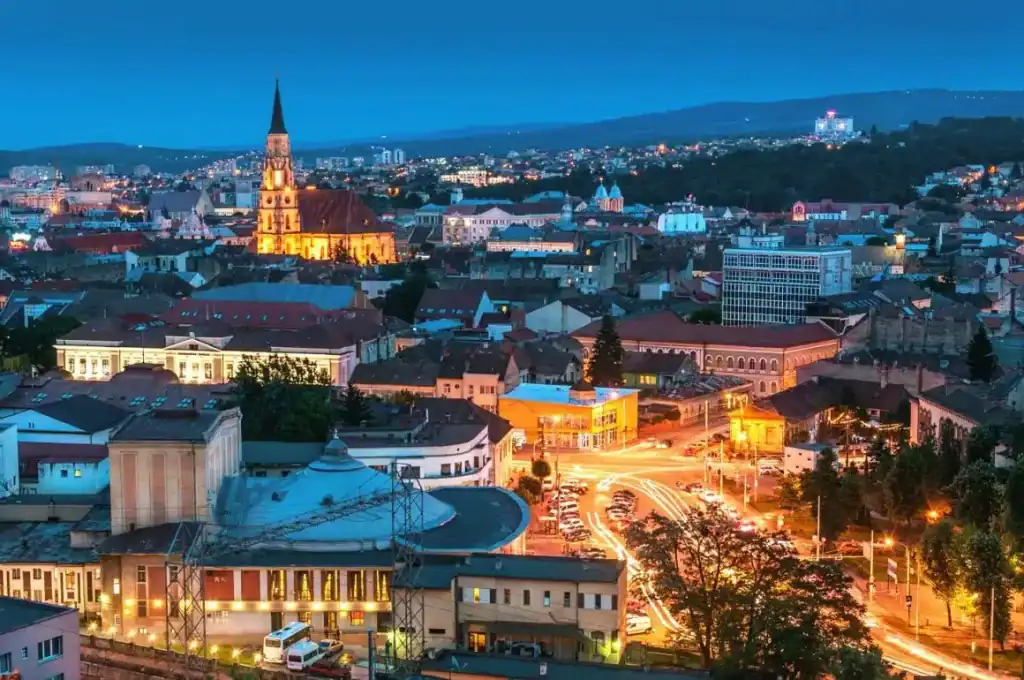 Cluj-Napoca city skyline with historic buildings and vibrant evening lights.