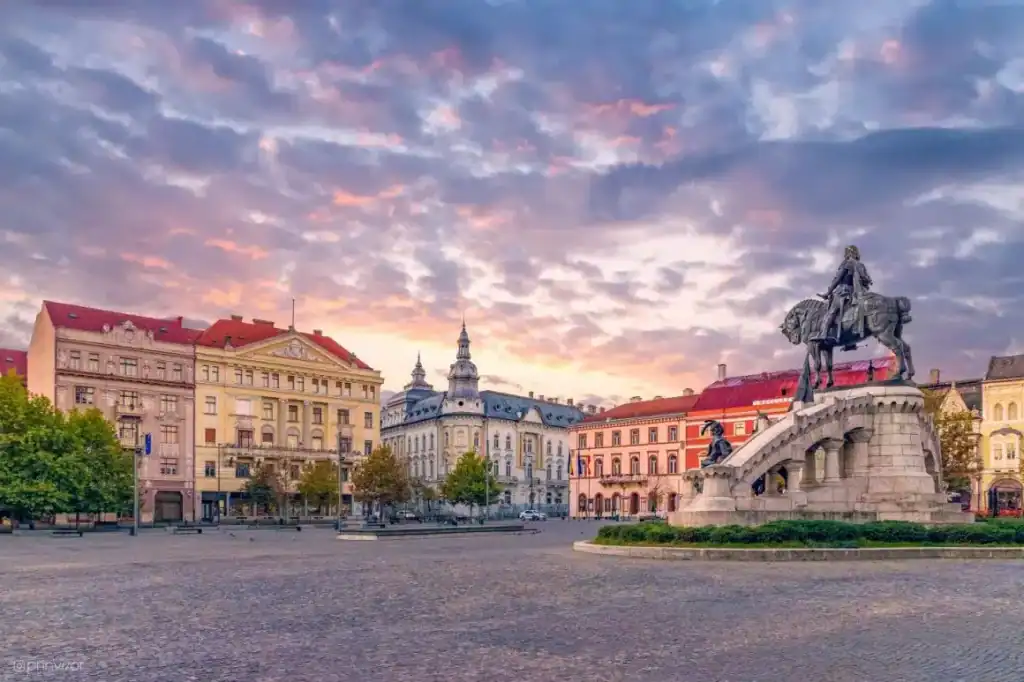 Historic Cluj Square with monument at sunset, perfect for private tours from Bucharest.