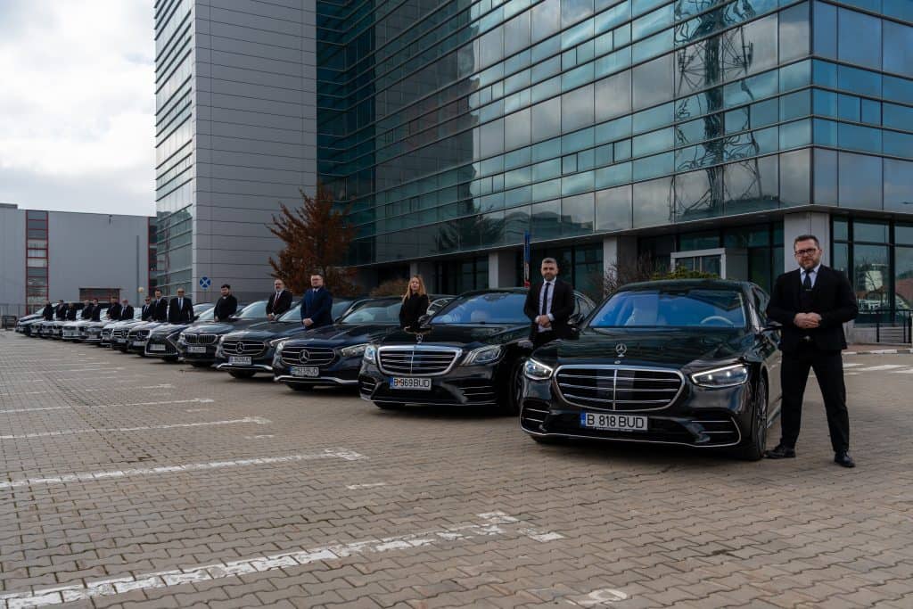 Luxury chauffeur cars lined up outside a modern building, with professional drivers ready for servic.