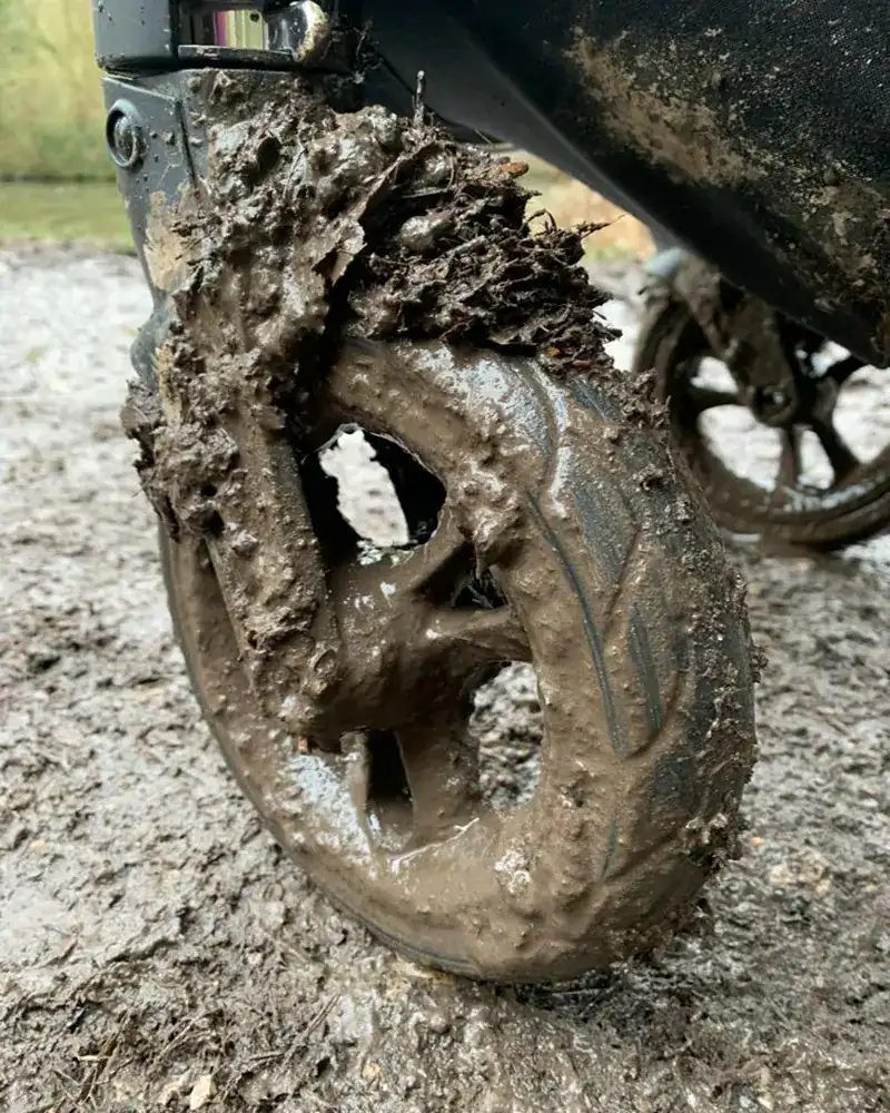 Close-up photo of a very muddy pushchair wheel