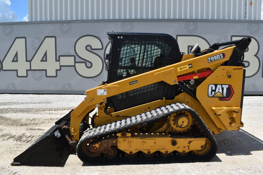 Yellow CAT compact track loader with black cab at heavy equipment auction.