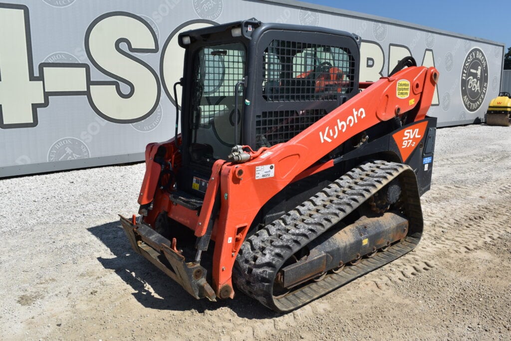 Kubota compact track loader at Bussey Bros Auction with heavy equipment background.