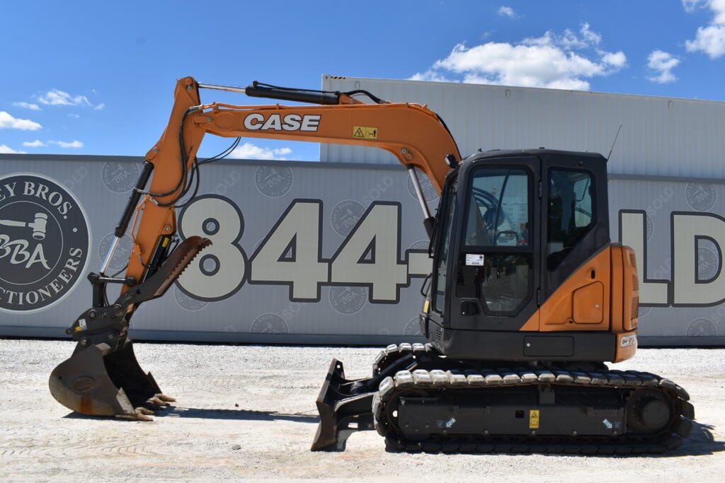 Orange Case mini excavator on auction lot with blue sky background.