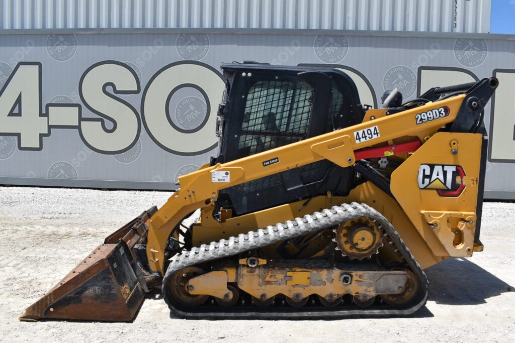 Yellow CAT compact track loader with bucket attachment at auction site.